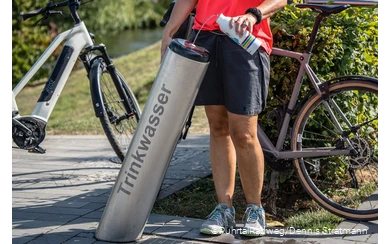 Radfahrerin füllt ihre Trinkflasche am Trinkbrunnen in Meschede mit Wasser auf