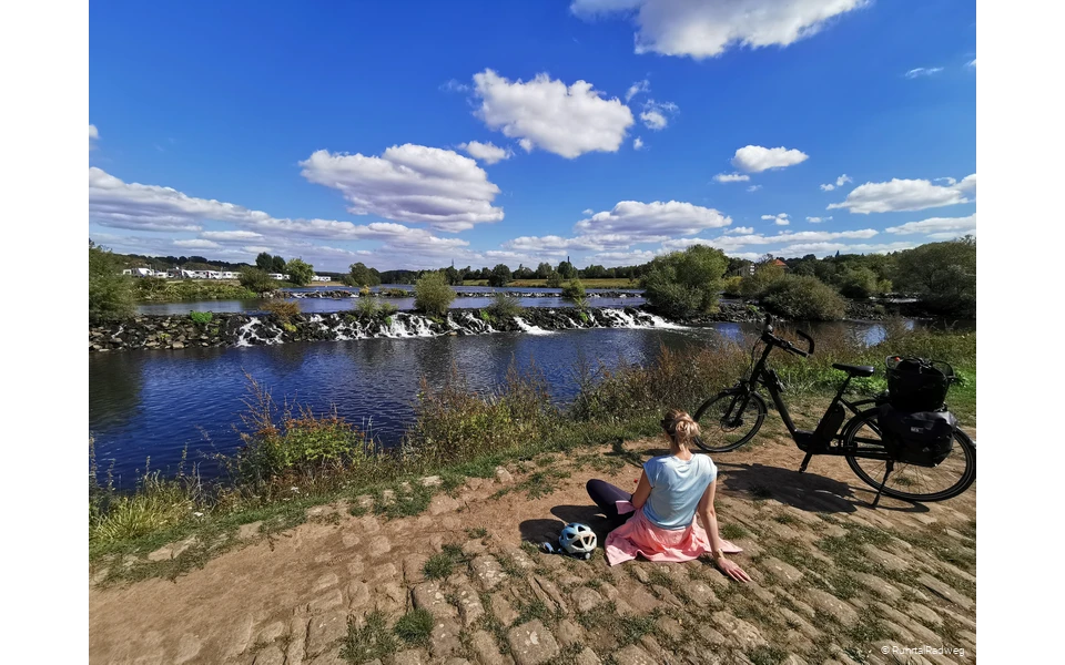 Radfahrerin sitzt vor den Kaskaden der Ruhr in Hattingen
