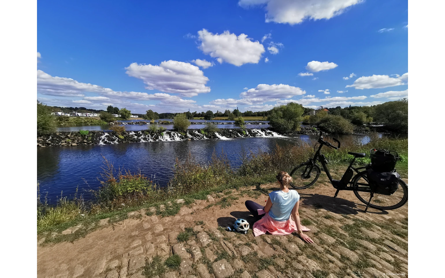 Radfahrerin sitzt vor den Kaskaden der Ruhr in Hattingen