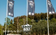 Drei Fahnen mit der Aufschrift Adventure Golf und einem Schild mit der selben Aufschrift.