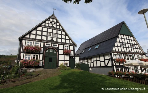 Zwei Fachwerkhäuser mit bunten Blumen an den Fenstern.