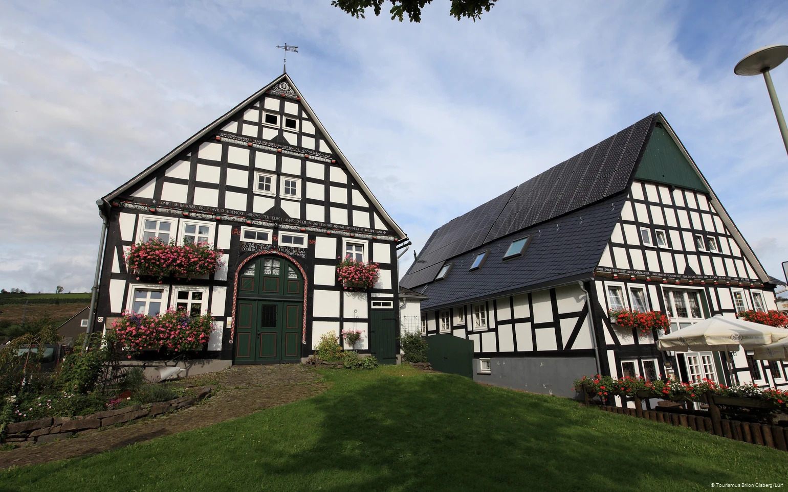 Zwei Fachwerkhäuser mit bunten Blumen an den Fenstern.