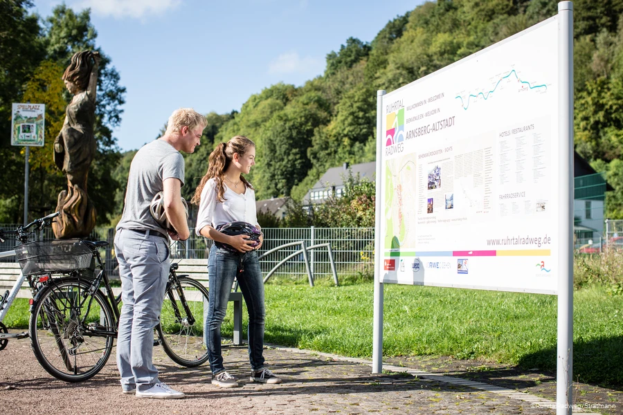 Paar mit Fahrr&auml;dern vor einer Stadtinformationstafel auf dem RuhrtalRadweg in Arnsberg