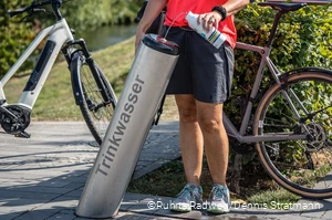 Radfahrerin füllt ihre Trinkflasche am Trinkbrunnen in Meschede mit Wasser auf