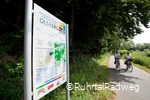 Stadtinformationsschild in Olsberg auf dem RuhrtalRadweg, an dem ein Paar auf Fahrrädern vorbei fährt